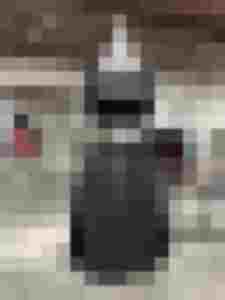 Graue Lodenschürze mit silbernem Bindegürtel über schwarzem Kleid auf einer Schneiderpuppe