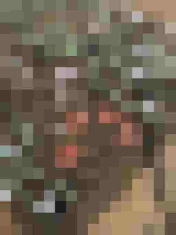 Detailreiche Stickerei mit Blumenmotiven auf transparentem Stoff vor Holzuntergrund.