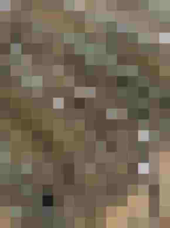 Filigrane Blumenstickerei auf transparentem Stoff, rustikaler Holztisch im Hintergrund.