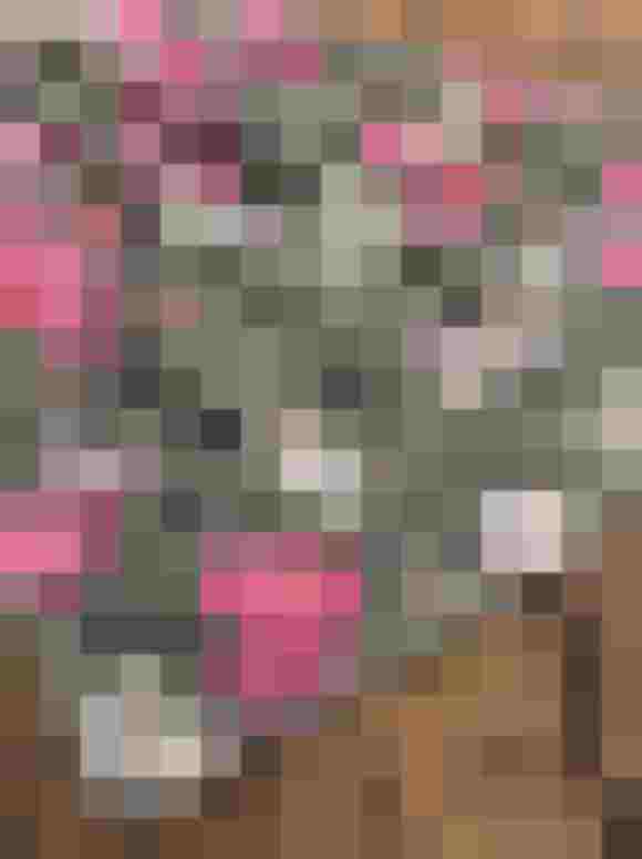 Blumenmuster-Schürze aus Baumwolle in Pink- und Grüntönen auf Holzuntergrund.