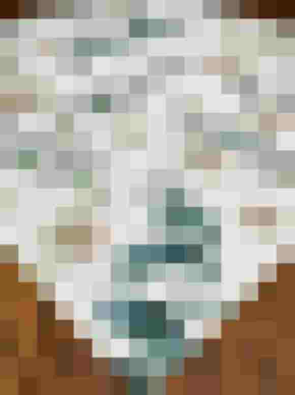 Stoff mit floralen Motiven in sanften Grüntönen auf einem Holztisch.