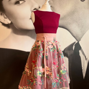 Schaufensterpuppe mit bestickter Spitzenschürze und rotem Oberteil